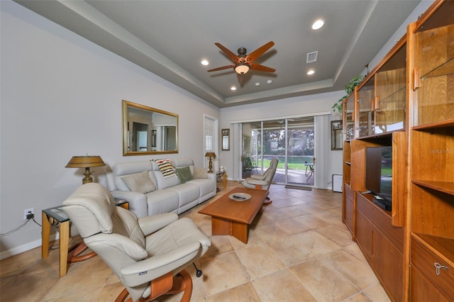 living room featuring ceiling fan and a raised ceiling