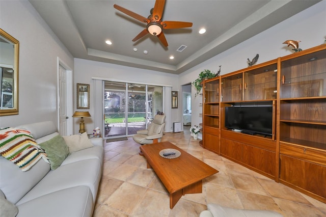 living room featuring a tray ceiling and ceiling fan