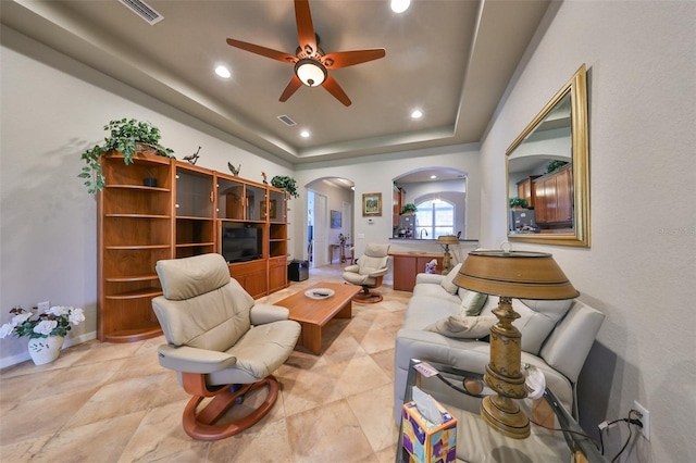 living room featuring ceiling fan and a tray ceiling