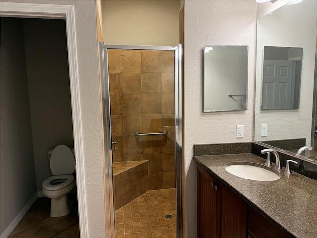 bathroom featuring tile patterned flooring, vanity, toilet, and a shower with shower door