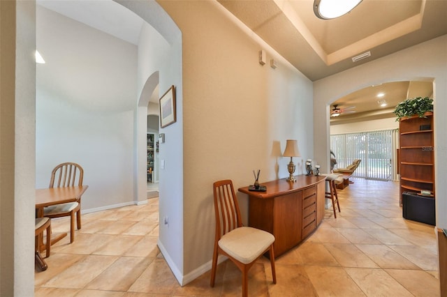 hallway with a raised ceiling and light tile patterned floors