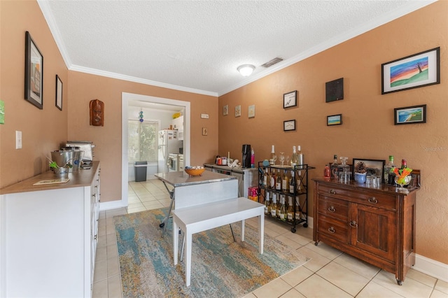 tiled dining room featuring a textured ceiling and ornamental molding