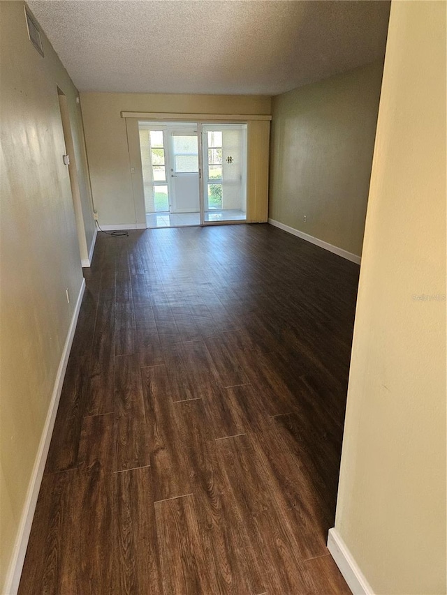 unfurnished room with a textured ceiling and dark hardwood / wood-style floors