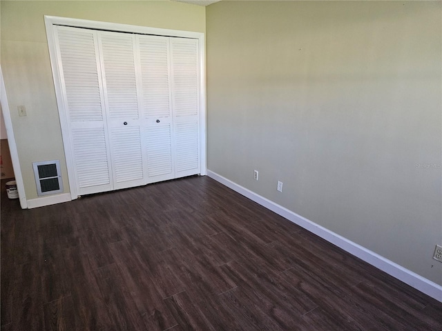 unfurnished bedroom with dark wood-type flooring and a closet