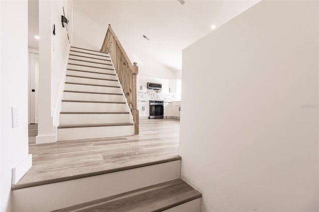 stairway featuring wood-type flooring and lofted ceiling