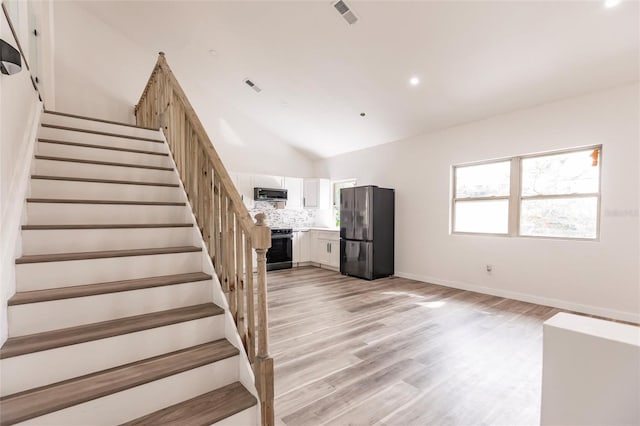 stairs featuring hardwood / wood-style floors and vaulted ceiling