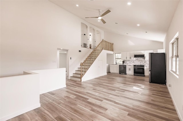 unfurnished living room featuring high vaulted ceiling, light hardwood / wood-style floors, sink, and ceiling fan