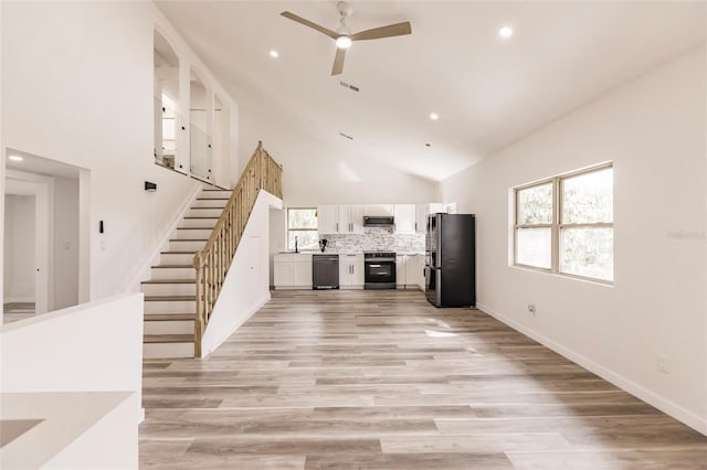 unfurnished living room with high vaulted ceiling, light hardwood / wood-style flooring, ceiling fan, and sink