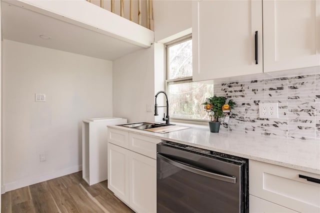 kitchen with light stone countertops, decorative backsplash, white cabinets, dishwasher, and light hardwood / wood-style flooring