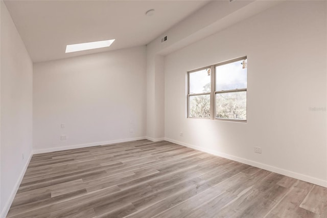 unfurnished room with a skylight and wood-type flooring