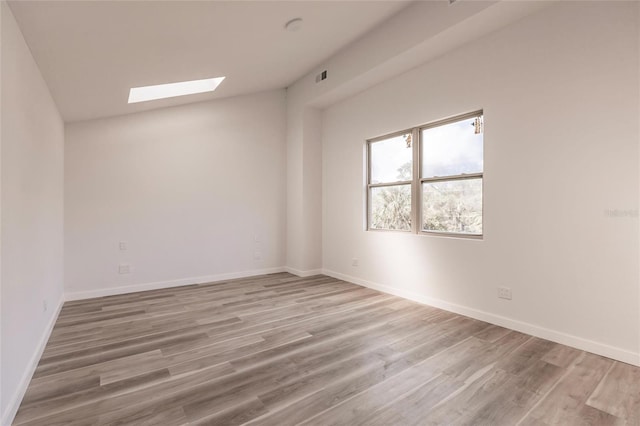21048 Peachland Blvd, Port Charlotte, FL 33954 - unfurnished room featuring a skylight, vaulted ceiling, light wood-style floors, and baseboards
