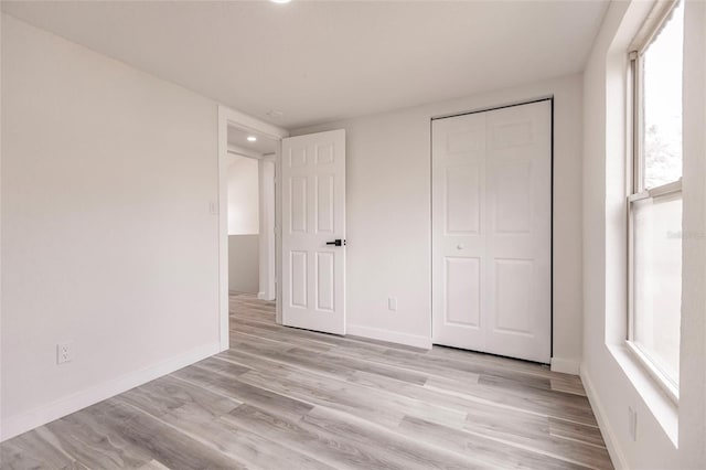 unfurnished bedroom with light wood-type flooring and a closet