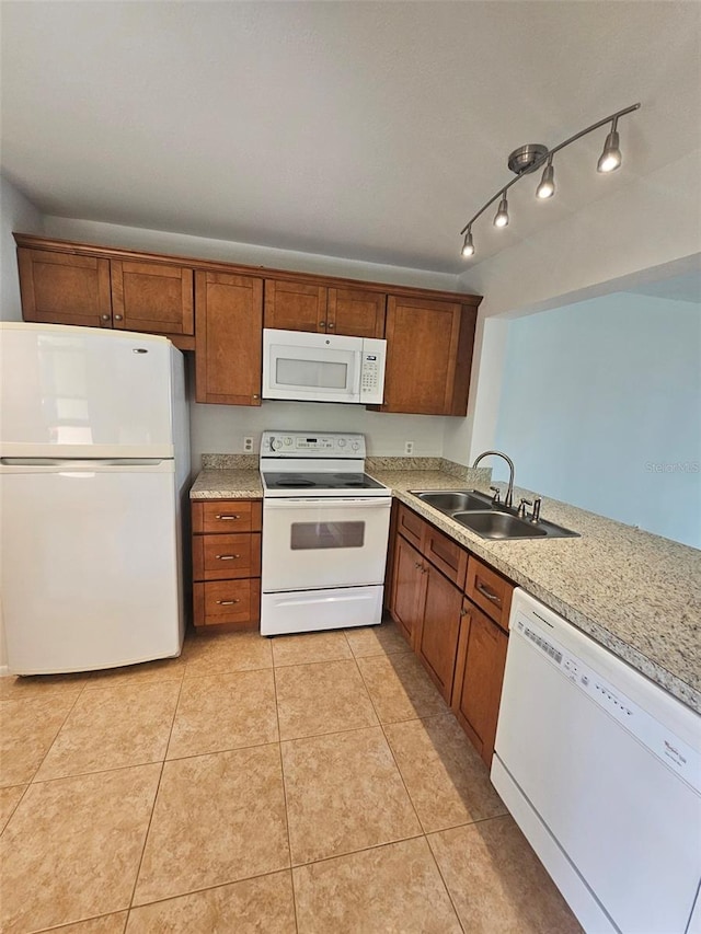 kitchen with sink, light stone counters, rail lighting, light tile patterned floors, and white appliances