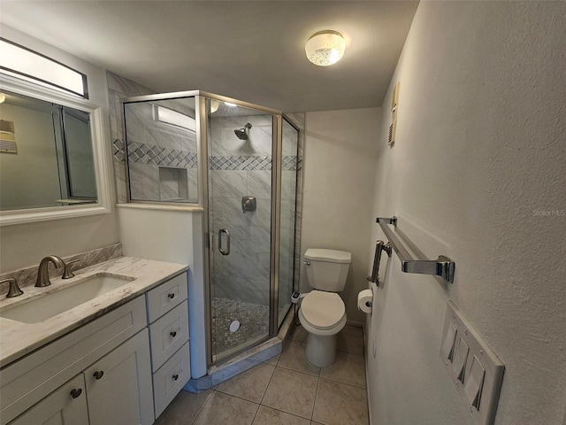 bathroom featuring tile patterned flooring, vanity, toilet, and a shower with door