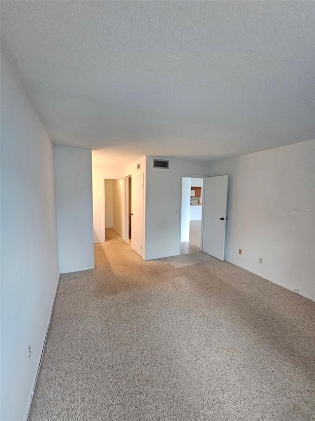 carpeted empty room with a textured ceiling