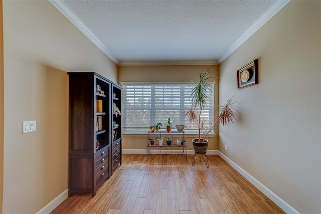 interior space featuring a textured ceiling, light wood-type flooring, and crown molding