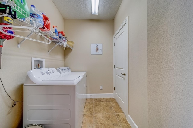 clothes washing area with washing machine and clothes dryer, light tile patterned flooring, and a textured ceiling