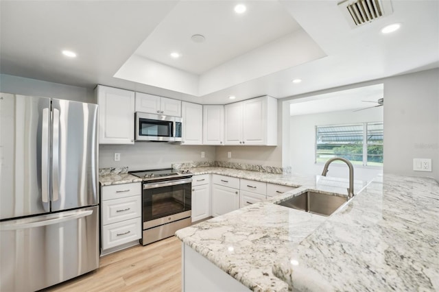 kitchen with visible vents, a raised ceiling, stainless steel appliances, white cabinetry, and a sink