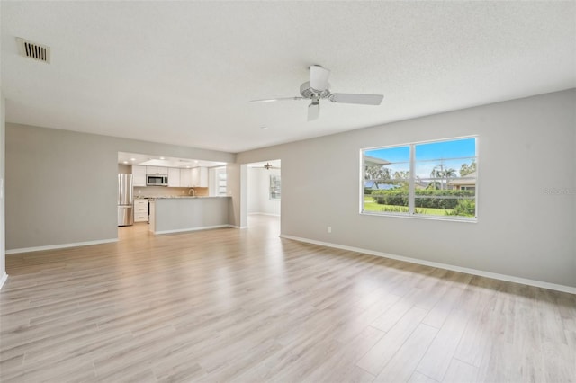 unfurnished living room with ceiling fan, a textured ceiling, and light hardwood / wood-style flooring