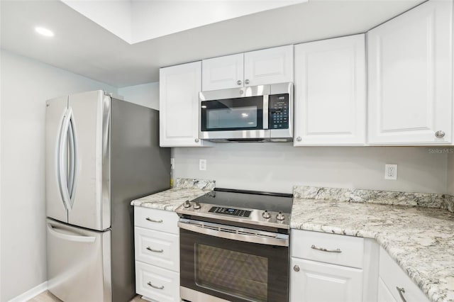 kitchen with light stone countertops, white cabinets, and stainless steel appliances