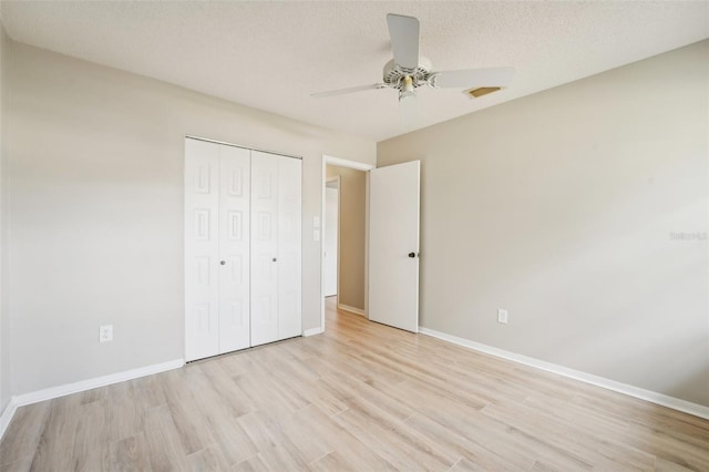 unfurnished bedroom featuring ceiling fan, a closet, a textured ceiling, and light wood-type flooring