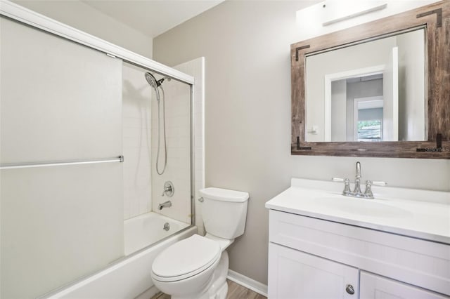 full bathroom with hardwood / wood-style floors, vanity, bath / shower combo with glass door, and toilet