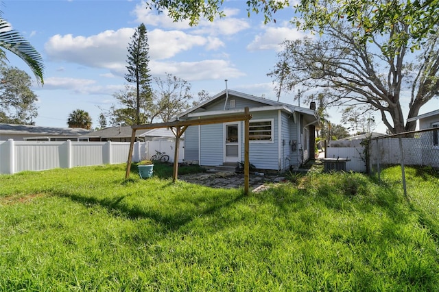 back of house featuring central AC unit and a yard