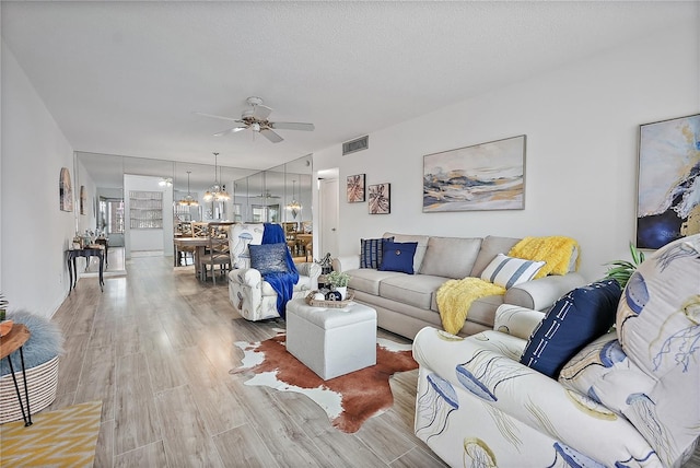 living room with hardwood / wood-style floors, ceiling fan, and a textured ceiling