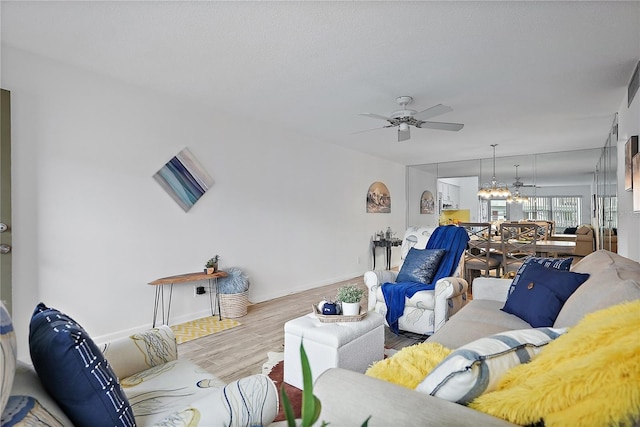 living room with ceiling fan with notable chandelier and light wood-type flooring