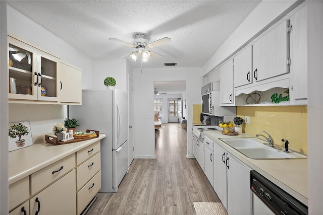 kitchen featuring light wood-type flooring, backsplash, a textured ceiling, white appliances, and sink