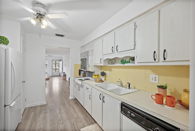 kitchen featuring white appliances, sink, ceiling fan, light wood-type flooring, and a textured ceiling