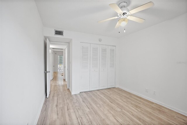 unfurnished bedroom featuring ceiling fan, light hardwood / wood-style floors, and a closet