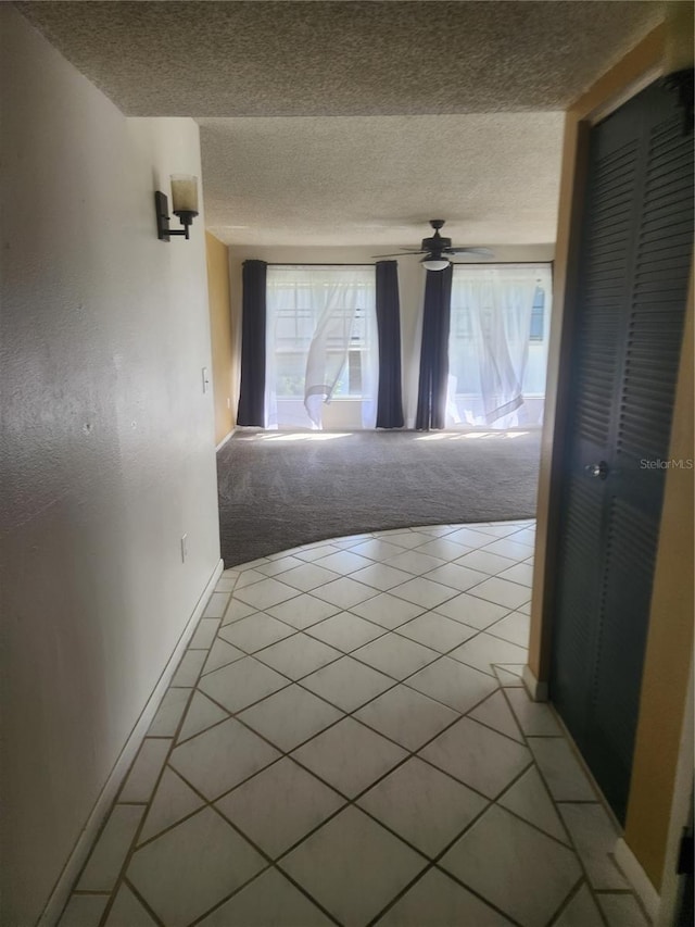 hall featuring a wealth of natural light, a textured ceiling, and light colored carpet