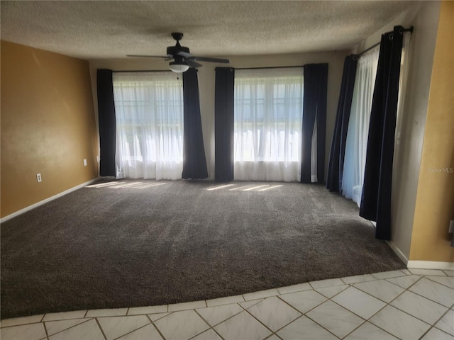 carpeted spare room featuring ceiling fan and a textured ceiling