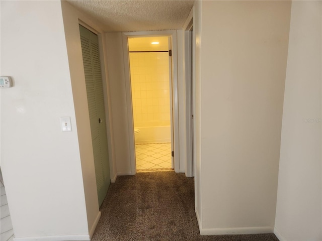 hall featuring a textured ceiling and dark carpet