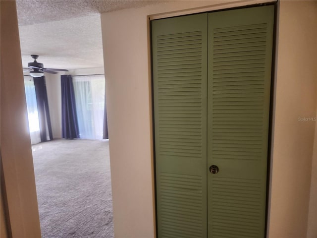 corridor with light colored carpet and a textured ceiling