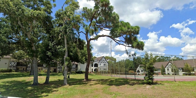 surrounding community featuring tennis court and a yard