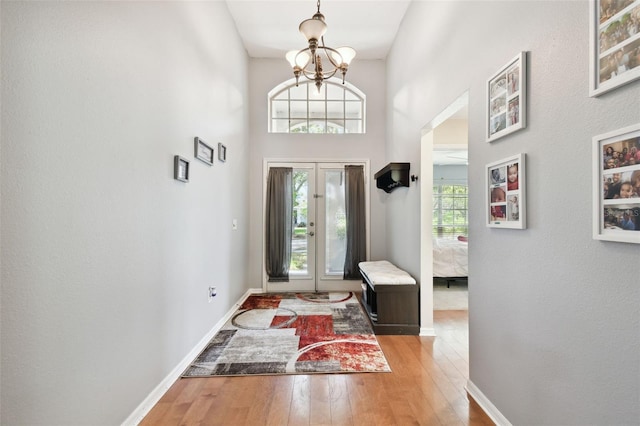 foyer entrance with a notable chandelier, wood-type flooring, and a towering ceiling