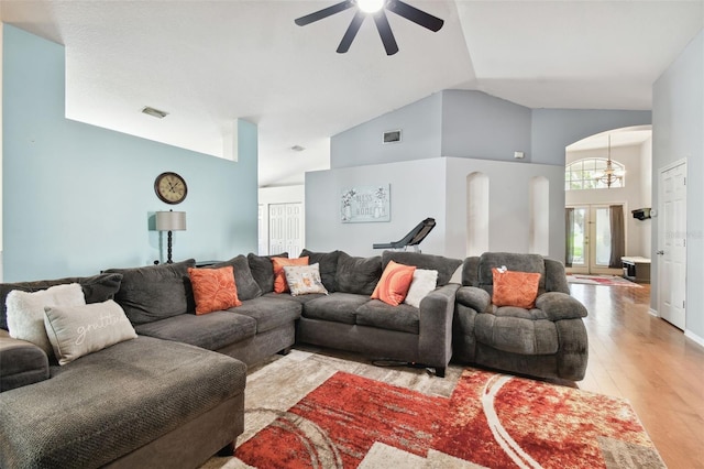 living room with ceiling fan with notable chandelier, light hardwood / wood-style floors, and high vaulted ceiling