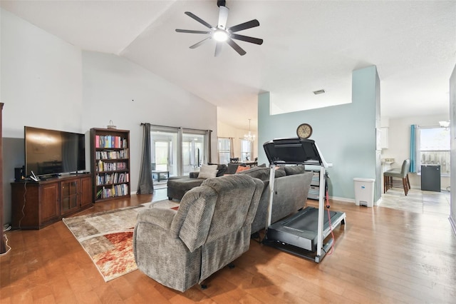 living room with light hardwood / wood-style flooring, a healthy amount of sunlight, and ceiling fan with notable chandelier