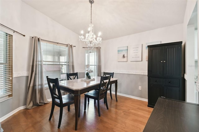 dining area with a chandelier, lofted ceiling, and hardwood / wood-style flooring