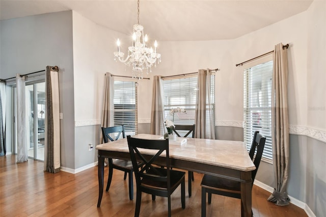 dining room featuring wood-type flooring, an inviting chandelier, and lofted ceiling