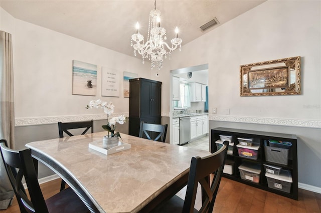 dining area with a chandelier, hardwood / wood-style floors, vaulted ceiling, and sink