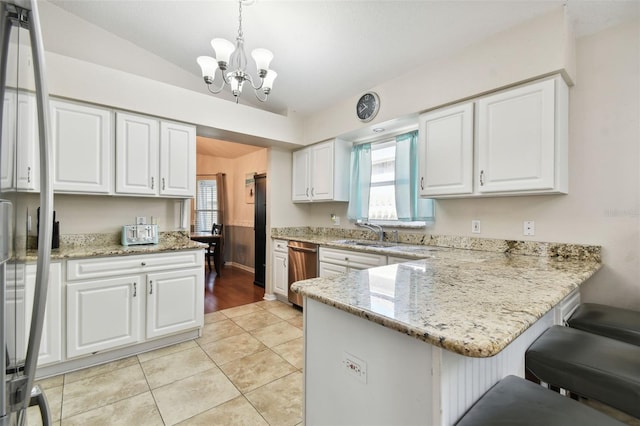 kitchen featuring kitchen peninsula, appliances with stainless steel finishes, a notable chandelier, white cabinetry, and hanging light fixtures