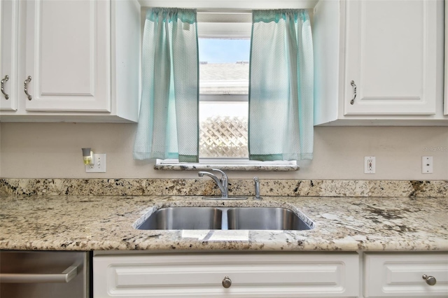 kitchen featuring light stone counters, sink, white cabinets, and stainless steel dishwasher