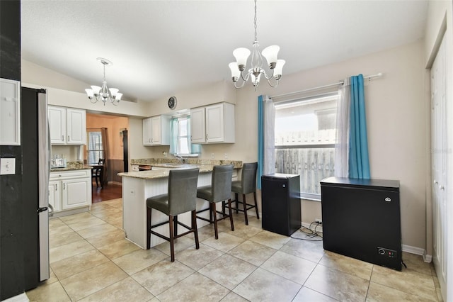 kitchen with kitchen peninsula, an inviting chandelier, decorative light fixtures, and white cabinetry