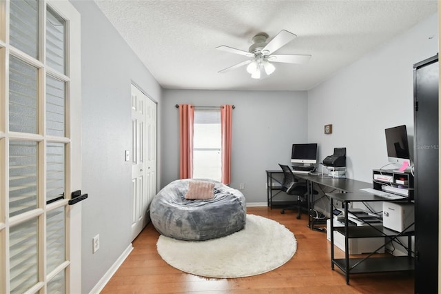 home office with ceiling fan, hardwood / wood-style floors, and a textured ceiling