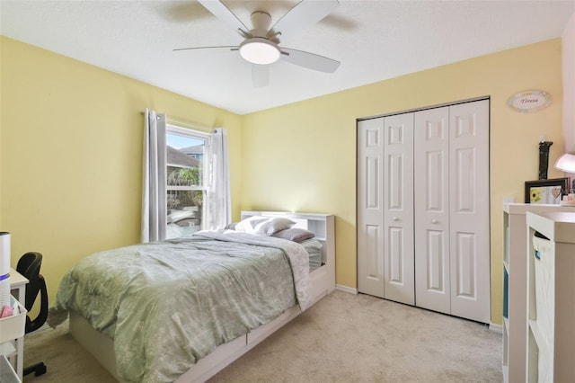 bedroom featuring ceiling fan, a closet, and light colored carpet