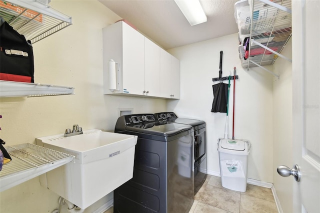 laundry area featuring cabinets, light tile patterned floors, washer and clothes dryer, and sink