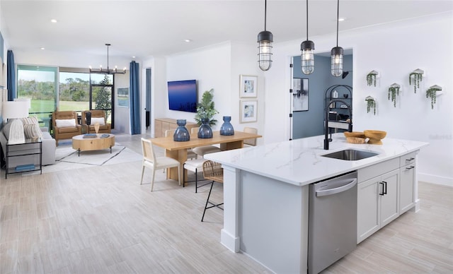 kitchen with a kitchen island with sink, hanging light fixtures, sink, and light stone countertops